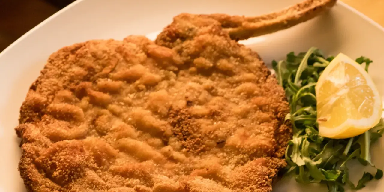 Cotolette al forno dorate e croccanti, servite con rucola fresca e una fetta di limone.