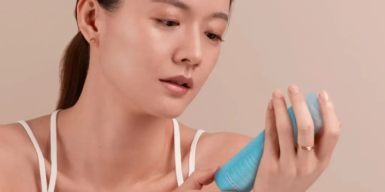 Une femme examine un tube de crème visage périmée, pas encore ouverte.