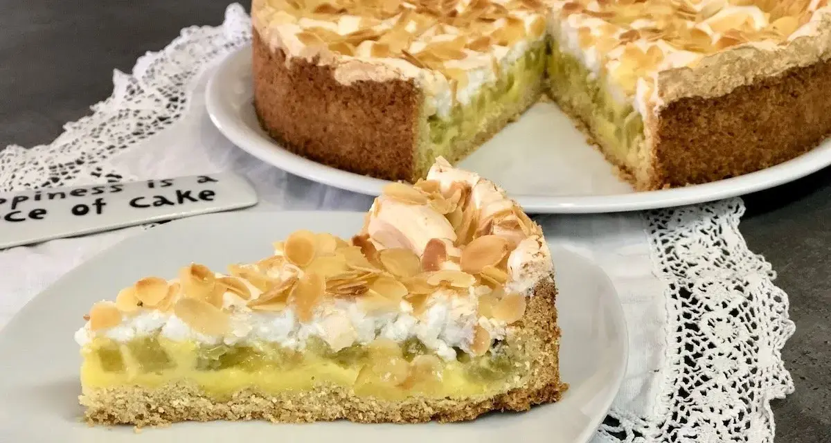 Ein köstlicher Rhabarberkuchen mit Pudding und Baiser, bestreut mit Mandelblättchen. Ein Stück Glück auf einem Teller.