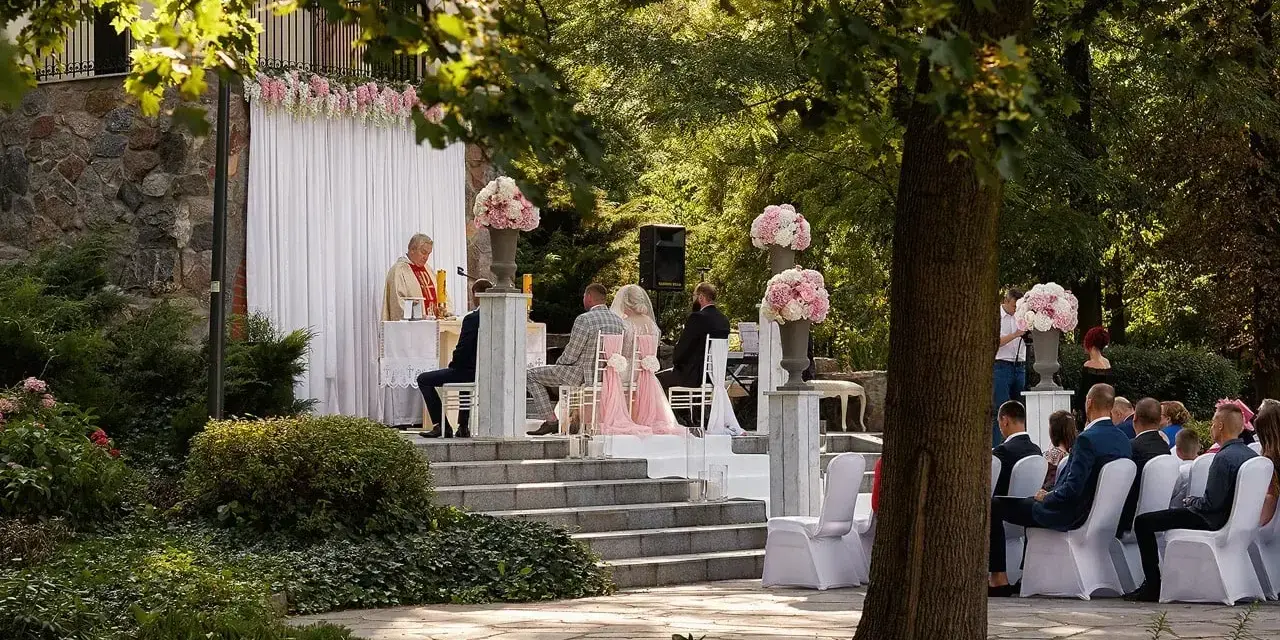 Piękna ceremonia ślubna w plenerze. Czy ksiądz może udzielić ślubu w plenerze? Tak, jak widać na zdjęciu, gdzie młoda para ślubuje sobie miłość przed ołtarzem na świeżym powietrzu.