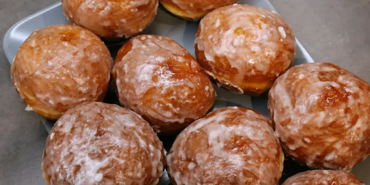 Szybkie pączki z piekarnika, oblane lukrem, kuszą apetycznym wyglądem. Idealne na szybką przekąskę.