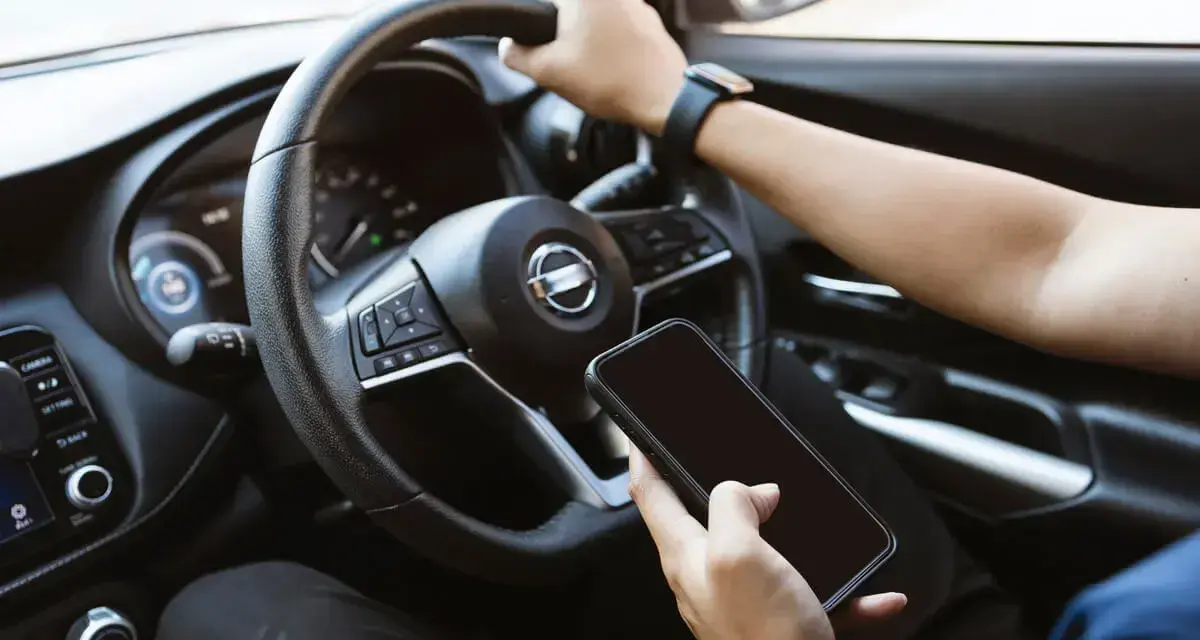 Fahrer hält Handy in der Hand, während er fährt. Hoffentlich wird er nicht geblitzt mit Handy in der Hand!