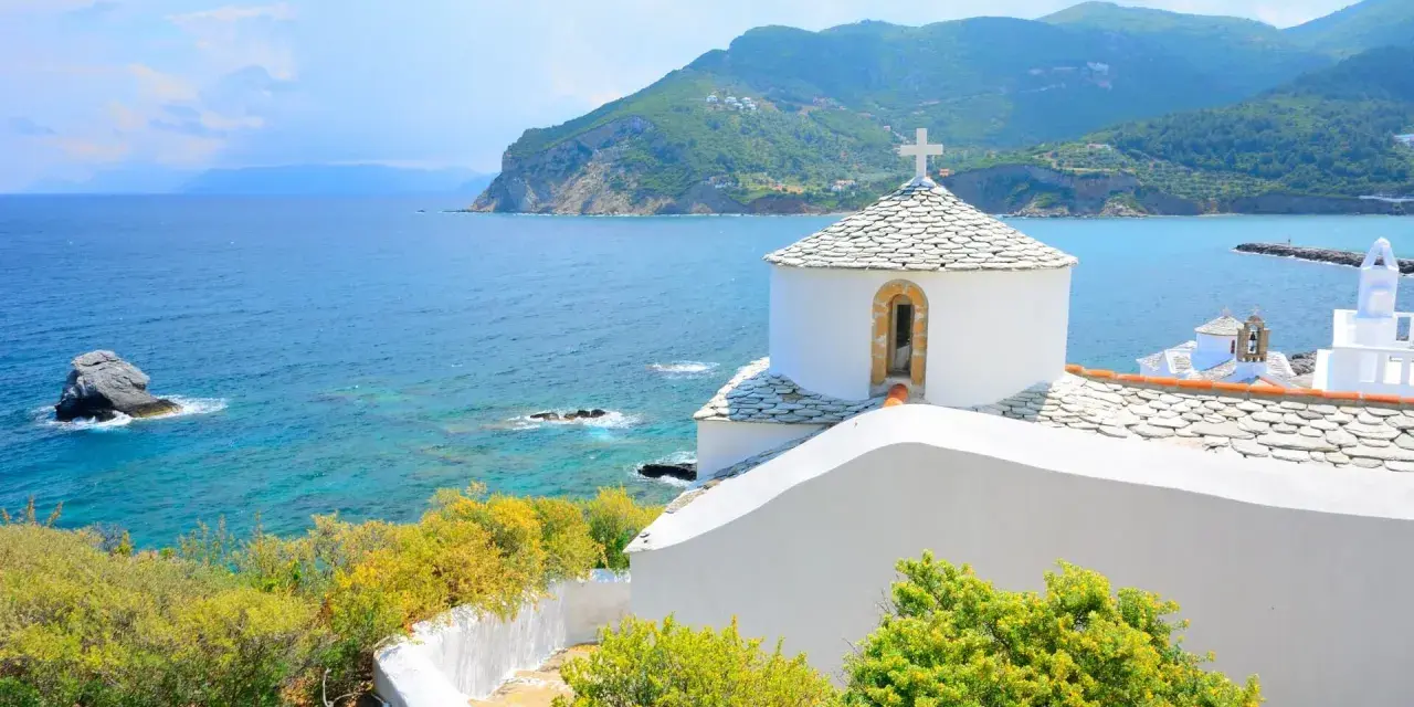 Malownicza zatoka i białe kościółki na wzgórzu. Idealne miejsce na skopelos wakacje.