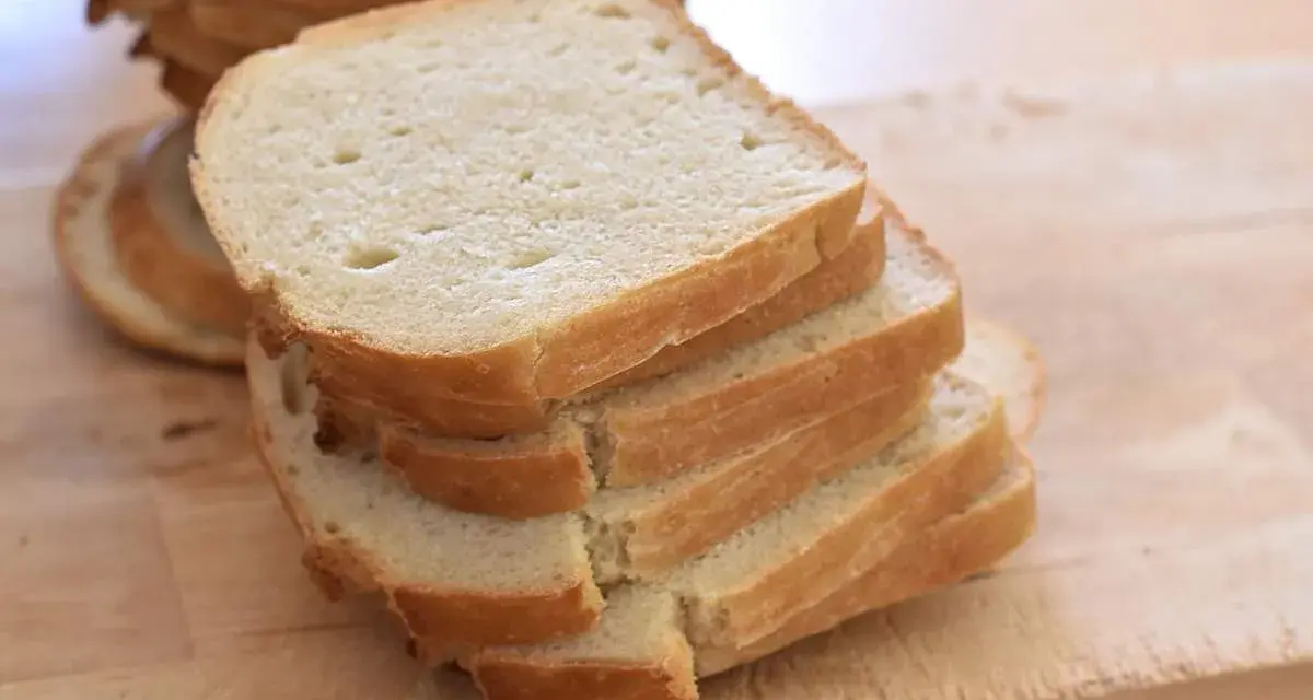 Gestapelte Scheiben eines hellen Sandwichbrots auf einem Holzbrett. Perfekt für ein einfaches Sandwich brot rezept.