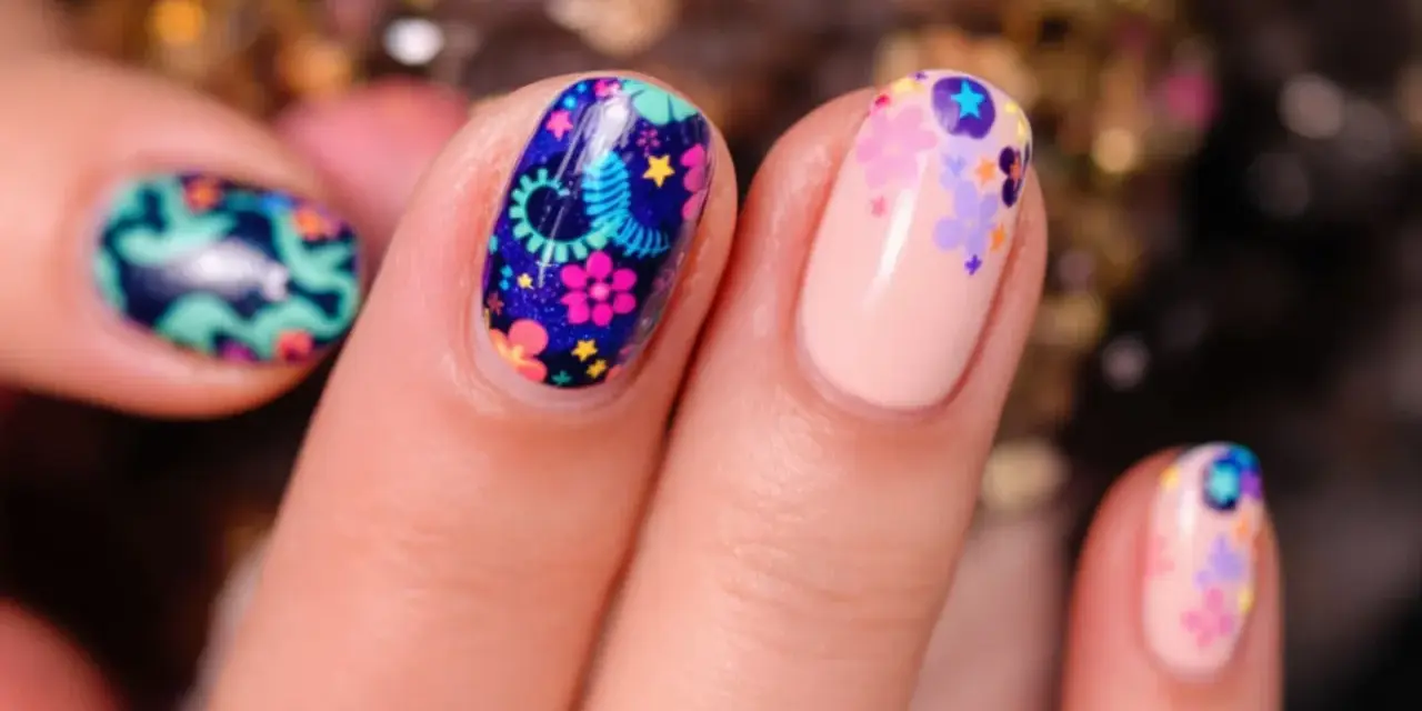Comment avoir de beaux ongles : des ongles décorés de motifs floraux colorés et de petites étoiles sur fond bleu nuit ou nude.
