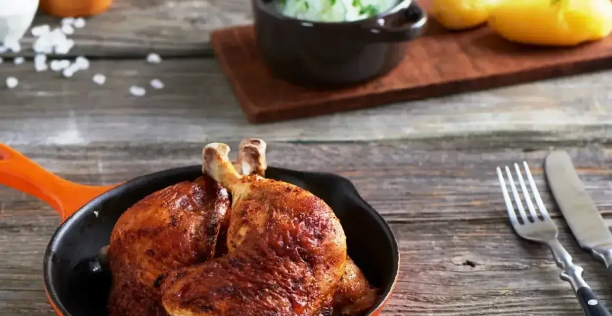 Złociste udka z airfryer w pomarańczowej patelni, obok ziemniaczki i surówka z ogórka. Pyszny obiad gotowy!