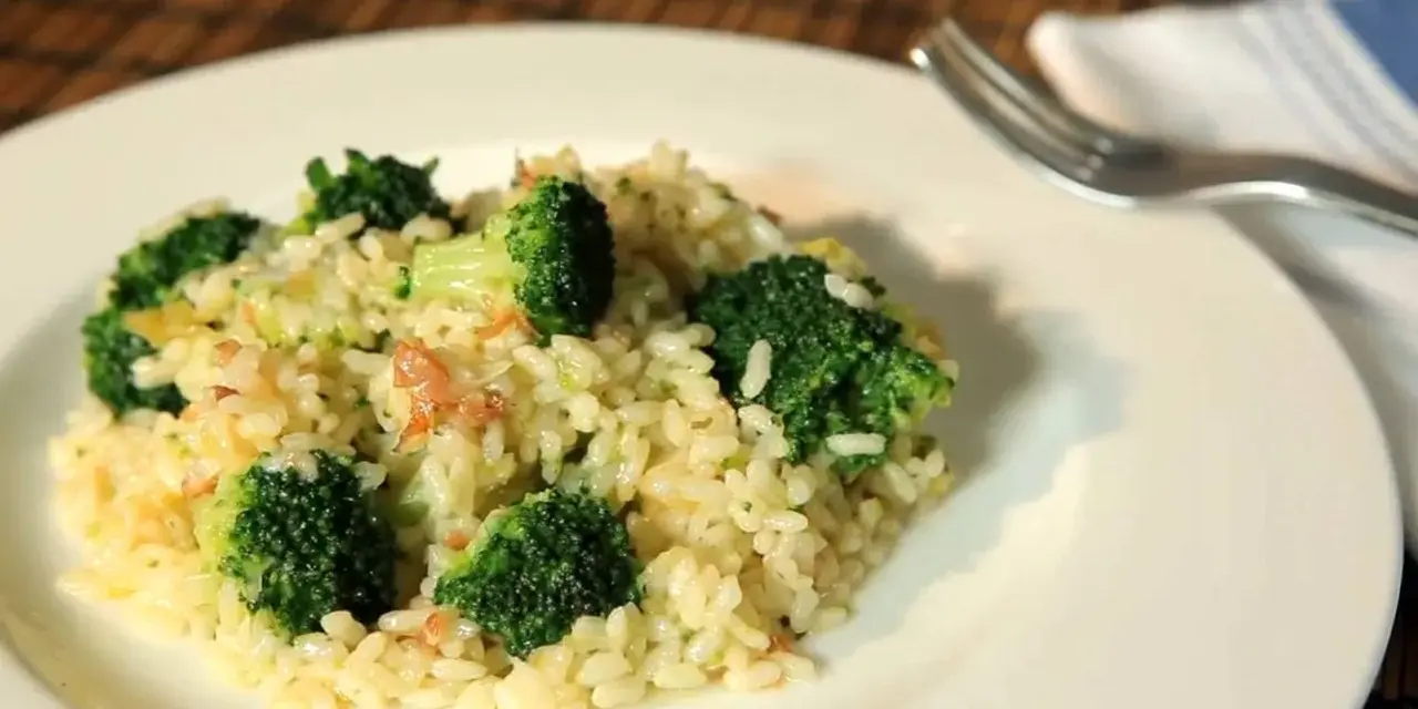 Delicioso arroz con brócoli cremoso, servido en un plato blanco con un tenedor al lado.