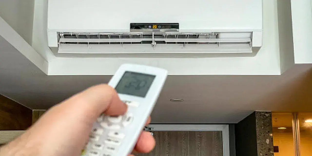Mano ajustando el control remoto del aire acondicionado a 20 grados, ideal para saber a cuanto poner el aire acondicionado en verano y refrescar el hogar.