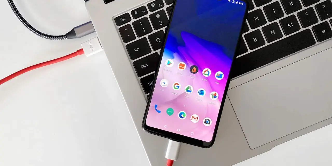 Smartfon podłączony kablem do laptopa, gotowy do przenoszenia zdjęć.