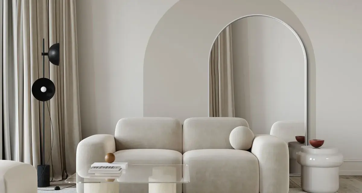 Nowoczesny salon z beżową kanapą, łukiem nad lustrem i stolikiem kawowym. Inspiracja, jak zrobić łuk w aranżacji wnętrz.
