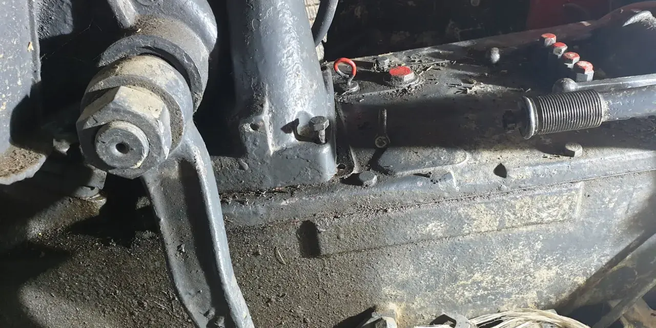 Elementy mechaniczne ciągnika Ursus C-360 podczas remontu skrzyni biegów. Widać ślady oleju i narzędzia.