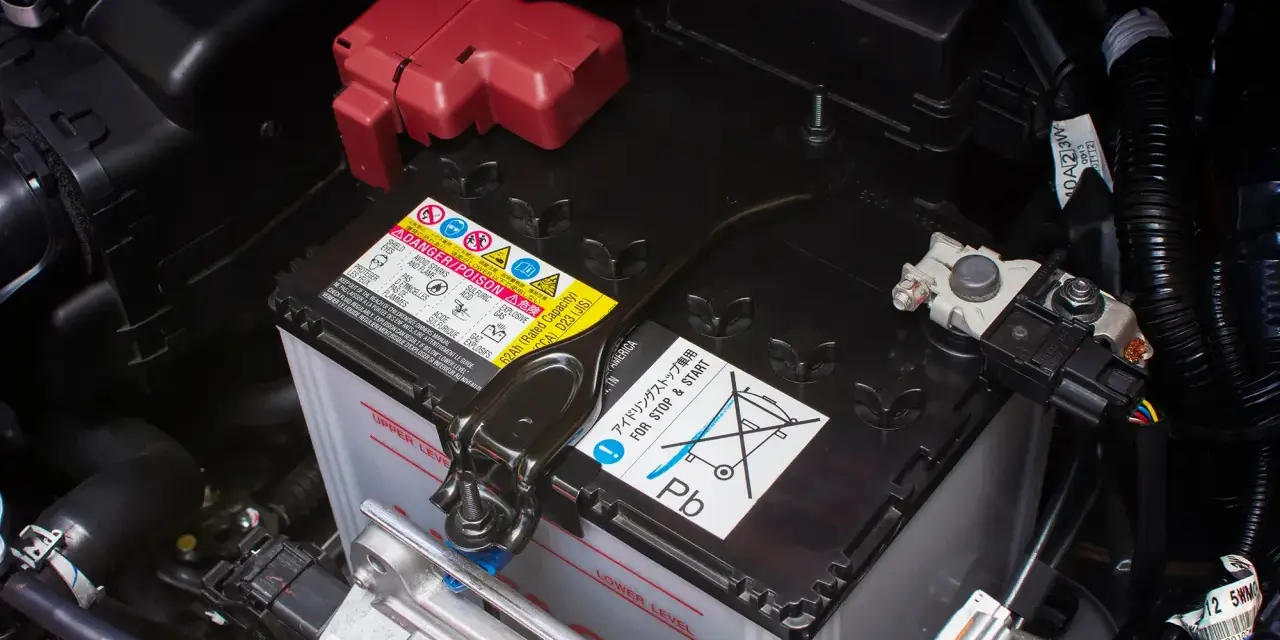 Autobatterie im Motorraum, mit Warnhinweisen. Die Batterie ist tiefentladen und muss ersetzt werden.