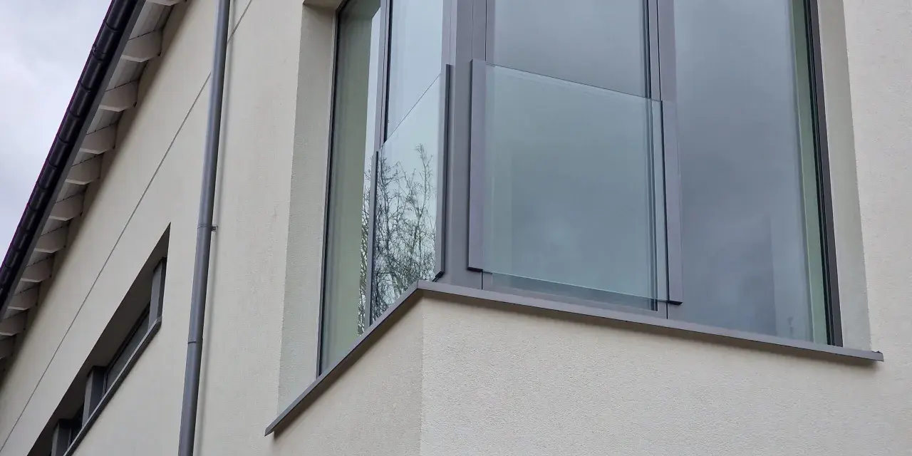 Nowoczesne portfenetry z przeszklonymi balustradami na jasnej elewacji.