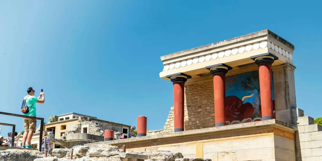 Zwiedzający robi zdjęcie fresku z bykiem w starożytnym pałacu w Knossos.