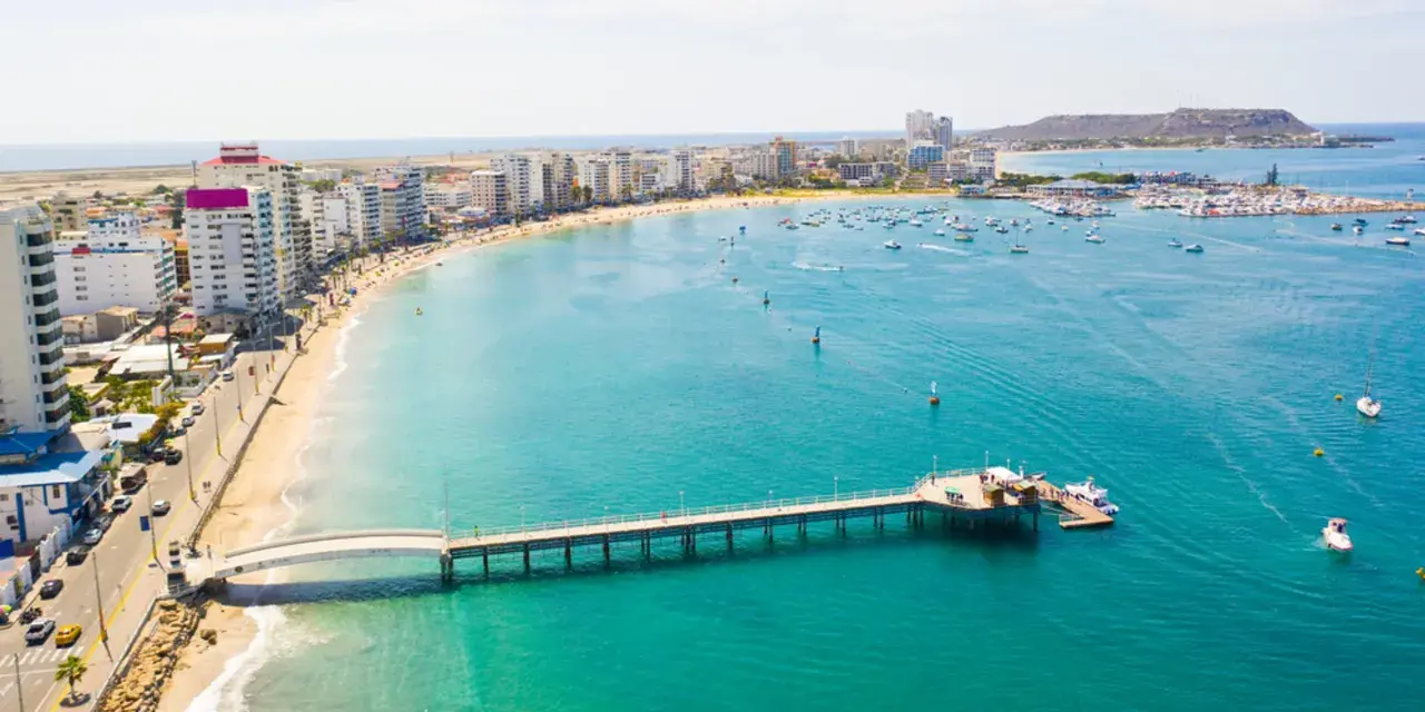 Malecón w Manta, Ekwador. Widok na plażę, budynki, molo i zatokę z łodziami. Tu właśnie leży Ekwador, kraj na równiku.