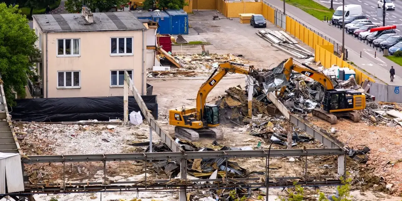 Dwie koparki pracują przy rozbiórce budynku. To przykład zgłoszenia rozbiórki budynku, gdzie widać postęp prac.