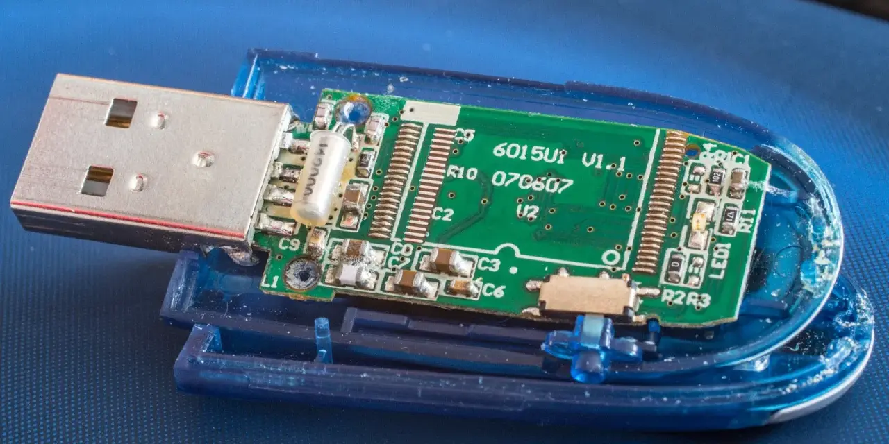 Rozłożony pendrive z widoczną zieloną płytką drukowaną i złączem USB. Widać elementy elektroniczne, oznaczenia jak "6015U1 V1.1" i "exfat" (choć nie widać go na obrazku, można założyć, że jest to format pliku).
