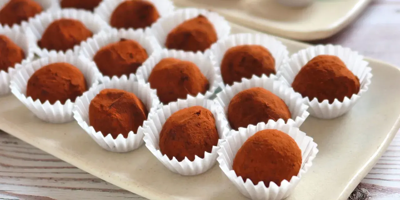Deliciosas trufas de chocolate cubiertas de cacao, presentadas en sus envoltorios blancos.