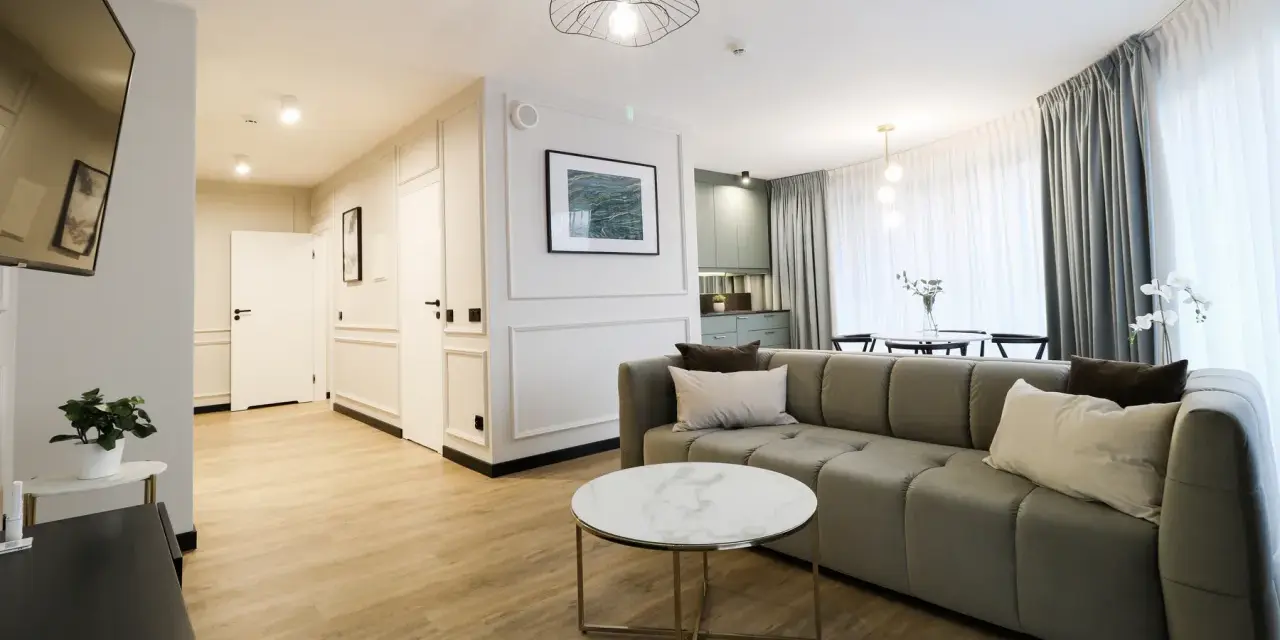 Nowoczesny apartament suite, z wygodną kanapą, stolikiem kawowym i widokiem na kuchnię.