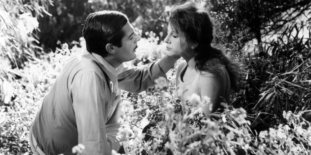 Un uomo e una donna in un campo fiorito, un'immagine che evoca il significato del sorpasso, un momento di intimità e cambiamento.