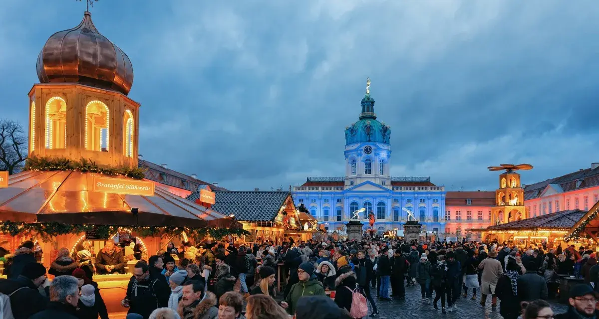 Besucher genießen den Weihnachtsmarkt vor dem beleuchteten Schloss Charlottenburg in Berlin.