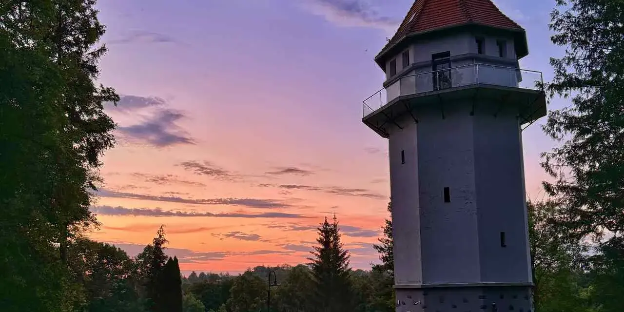 Wieża widokowa w Rynie, jedna z lokalnych atrakcji, na tle zachodzącego słońca.
