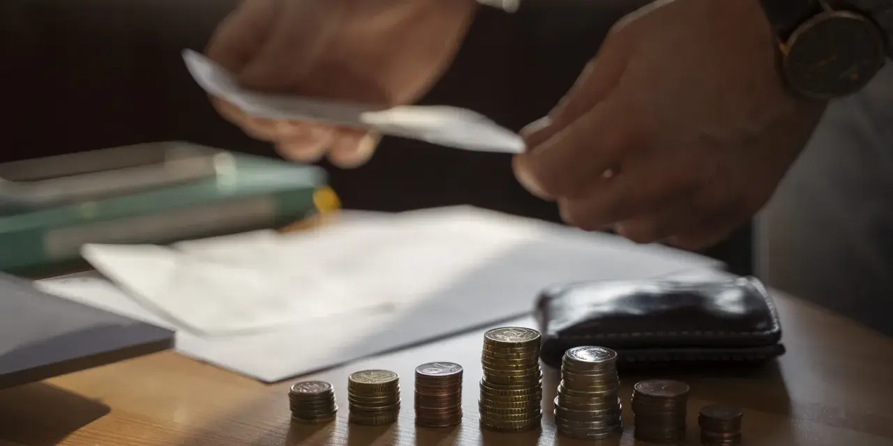 Ręce liczą pieniądze nad stosem monet, symbolizującym trudną sytuację finansową i potencjalną upadłość przedsiębiorcy.