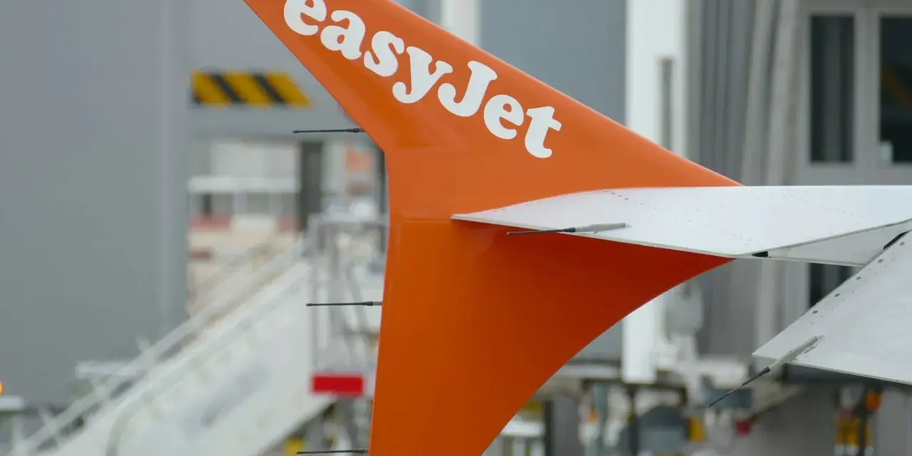 Pomarańczowe usterzenie EasyJet z białym logo, gotowe do lotu. Sprawdź wymiary bagażu podręcznego przed podróżą.