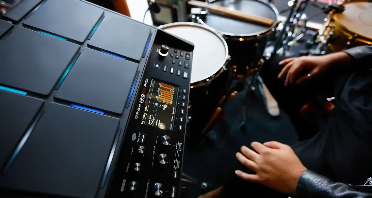 Nowoczesny sampler perkusyjny Roland SPD-SX PRO gotowy do tworzenia rytmów. W tle widoczne elementy zestawu perkusyjnego.
