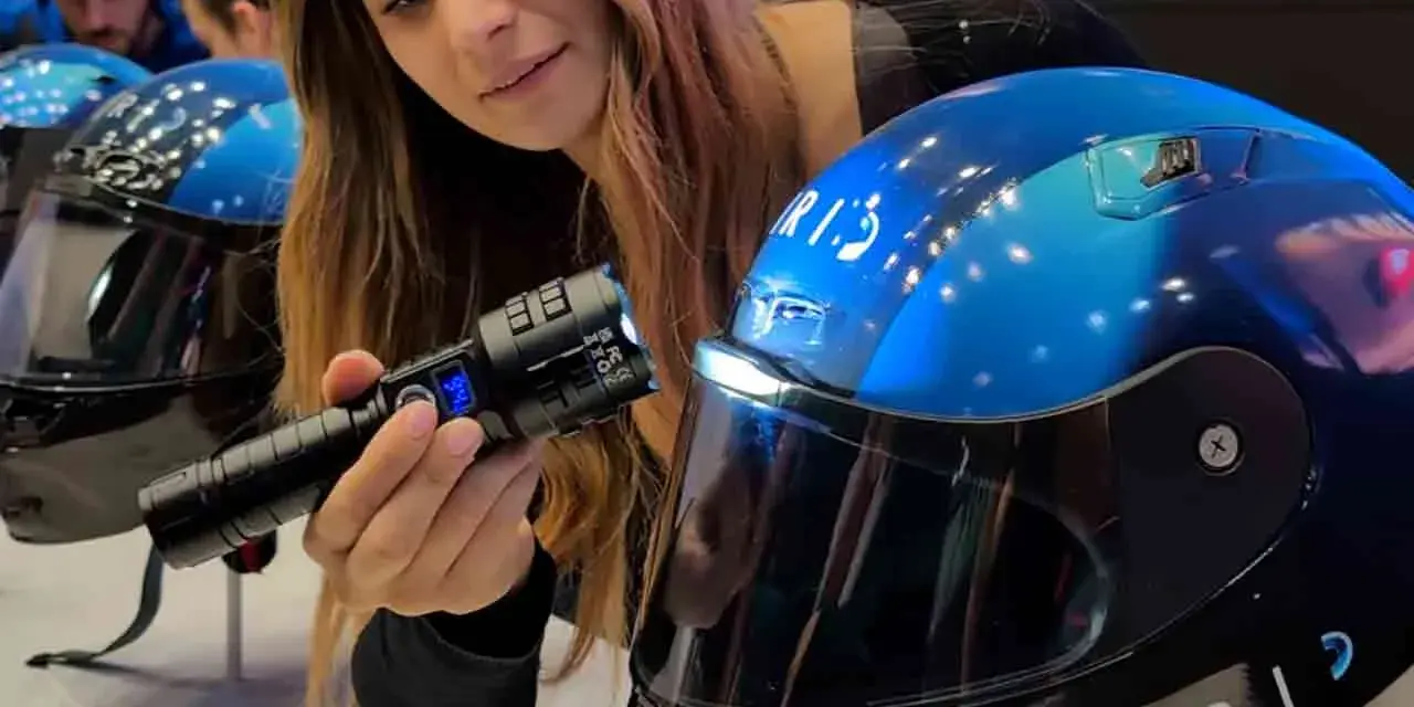 Donna mostra un casco da moto blu con visiera, evidenziando la sua importanza per la sicurezza. È bene che il casco sia dotato di visiera.