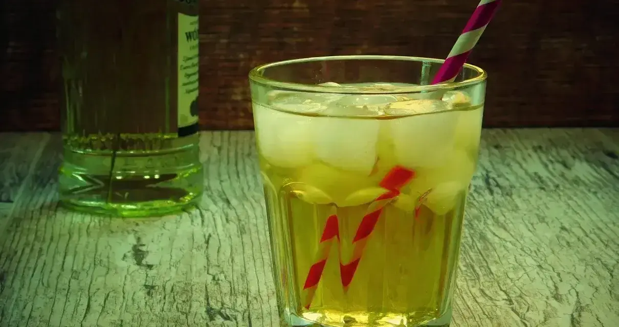 Orzeźwiający drink z lodem i słomką, idealny do przygotowania według przepisu na French Martini. Obok butelka alkoholu.