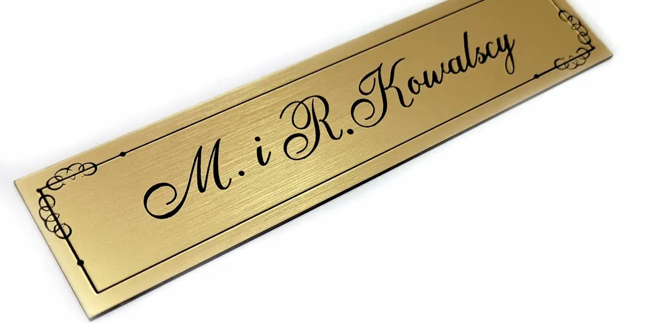Elegancki, złoty szyld z napisem "M. i R. Kowalscy" w ozdobnej ramce.
