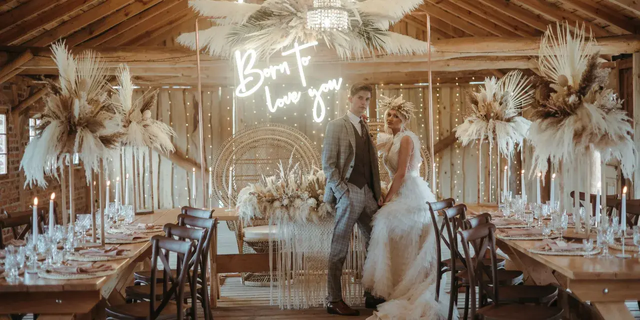Elegancka sala weselna stodoła z parą młodą, neonem "Born to love you" i boho dekoracjami z traw pampasowych.