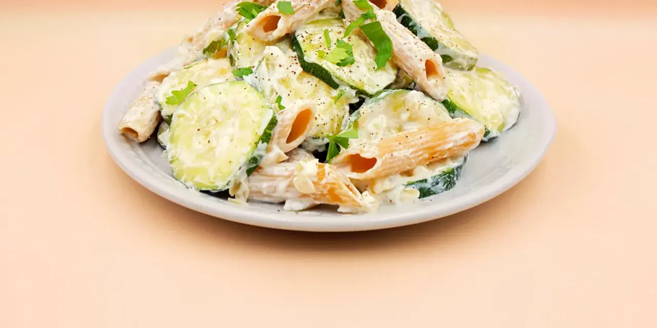 Makaron z cukinii przepis: penne w kremowym sosie z plasterkami cukinii, posypane natką pietruszki i pieprzem.
