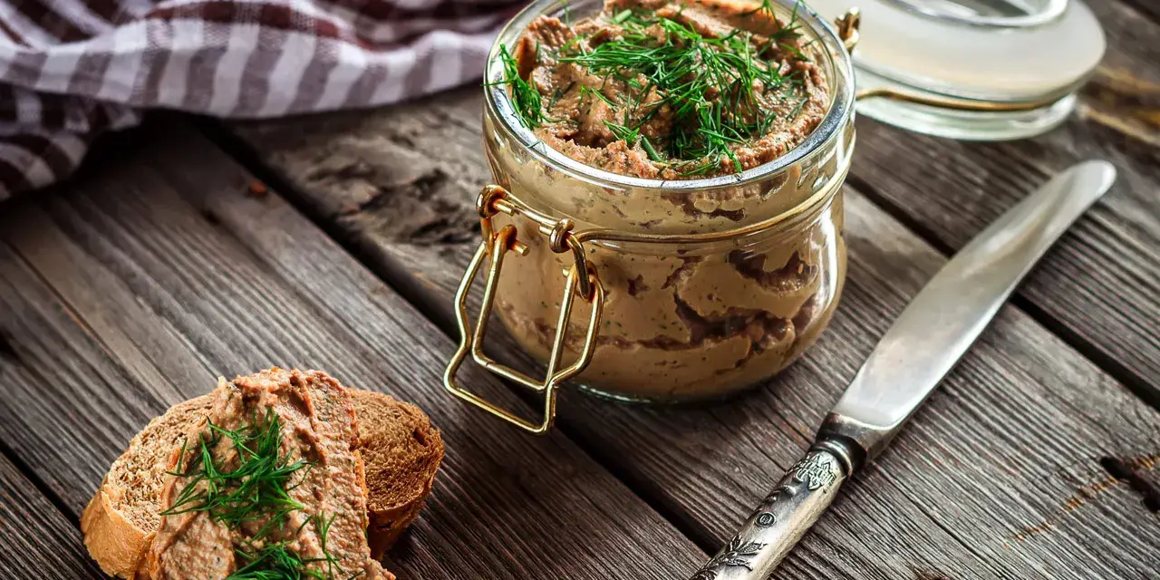 Un tarro de rillettes, paté de cerdo desmenuzado, con eneldo fresco, servido sobre pan tostado.