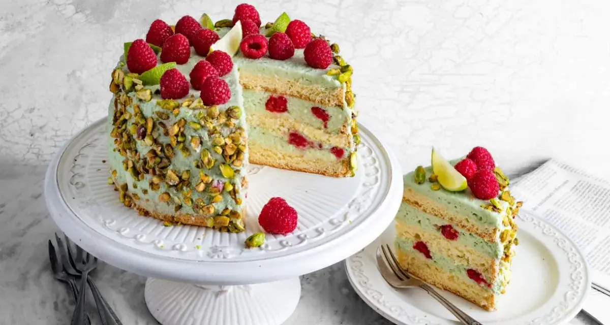 Wyjątkowy tort pistacjowy z malinami i limonką, ozdobiony chrupiącymi pistacjami. Idealny na każdą okazję.