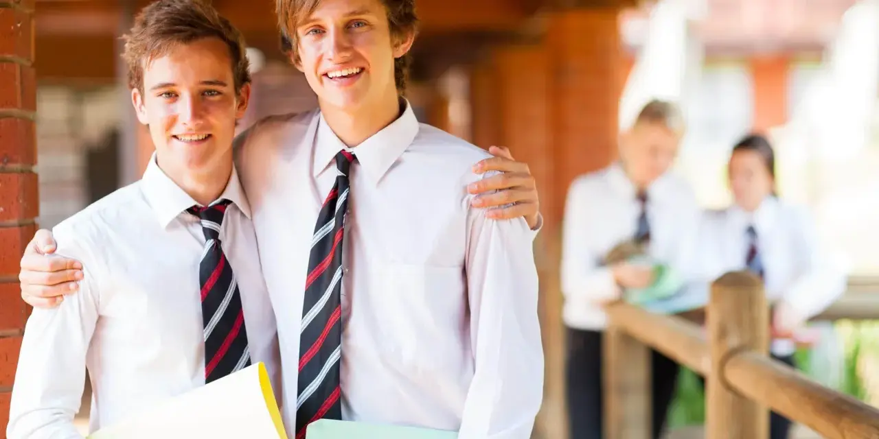 Deux adolescents souriants, portant des chemises blanches et des cravates, profitent de leurs vacances scolaires en Irlande.