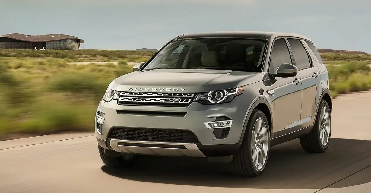 Szary Land Rover Discovery Sport w ruchu, z widocznym napisem "DISCOVERY". Czyżby kolejne awarie?