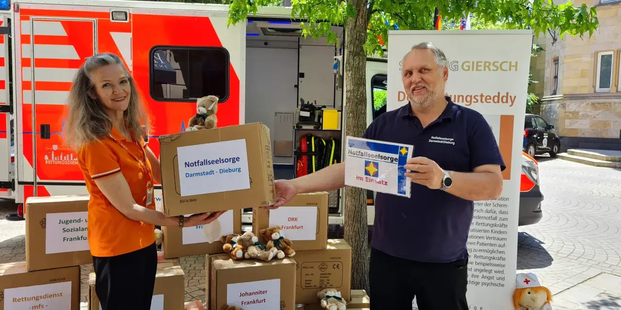 Zwei Personen vor einem Rettungswagen präsentieren Kartons für die Notfallseelsorge. Sie sind bereit, als Notfallseelsorger zu helfen.
