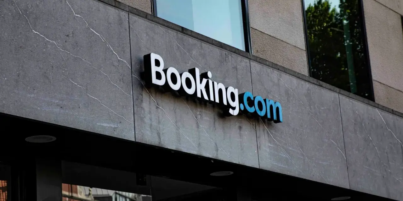 Logo Booking.com na szarym, kamiennym budynku. Planujesz podróż i szukasz najlepszych ofert? Z booking cashback Twoje wakacje będą tańsze!