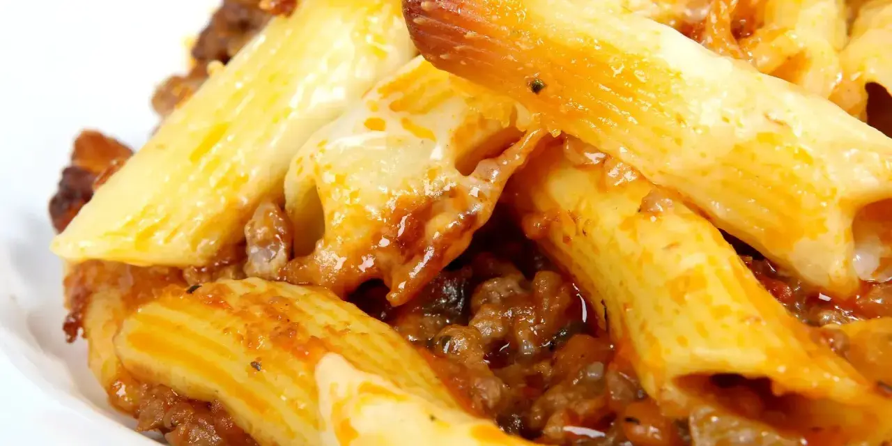 Macarrones con carne y queso fundido, cubiertos con salsa de tomate.