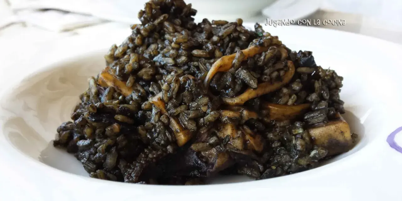Un plato de arroz negro con trozos de calamar, servido en un cuenco blanco.