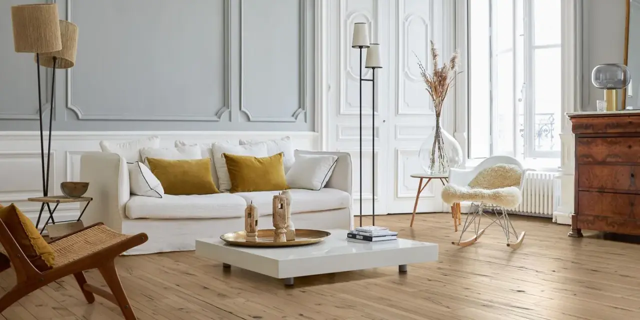 Stilvolles Wohnzimmer mit hellem Parkettboden, der durch regelmäßige Parkett Pflege glänzt. Gemütliche Couch, Sessel und ein moderner Couchtisch.