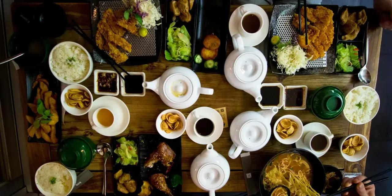 Mesa llena de platos asiáticos, teteras y tazas. Una experiencia culinaria en un restaurante sensorial.