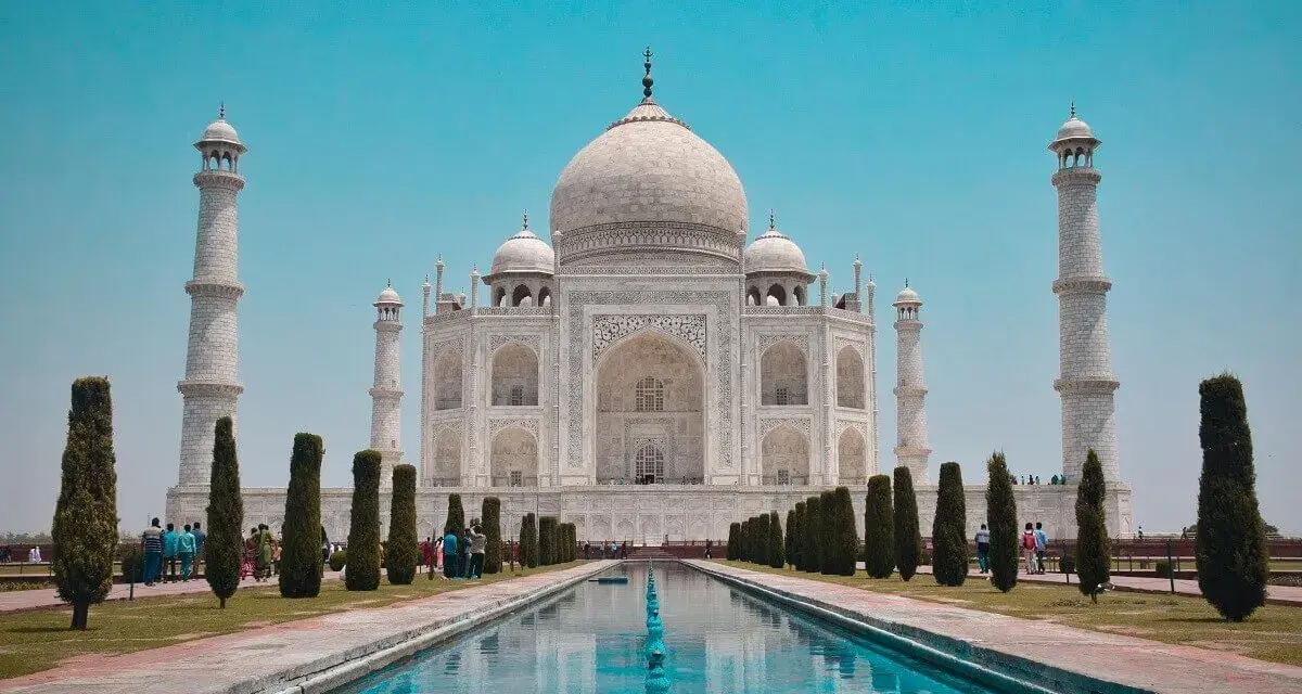 El Taj Mahal, en Agra, India, se alza majestuoso con su cúpula blanca y minaretes, reflejado en el estanque.