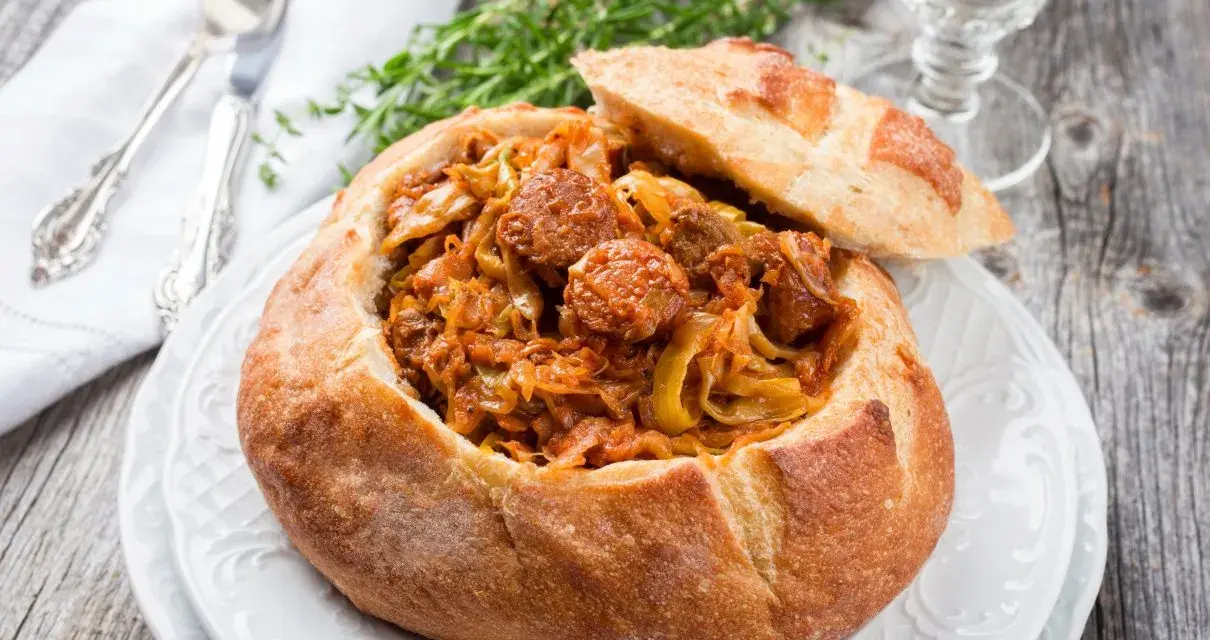 Bigos staropolski w chlebie, sycące danie z kapusty i kiełbasy, idealne na zimowe wieczory.