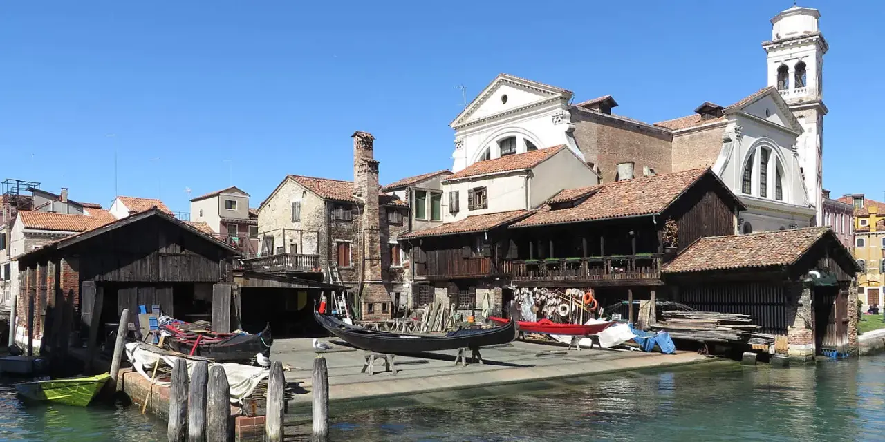 Lo squero di San Trovaso, con gondole in lavorazione e un campanile sullo sfondo, riflette la tradizione veneziana.