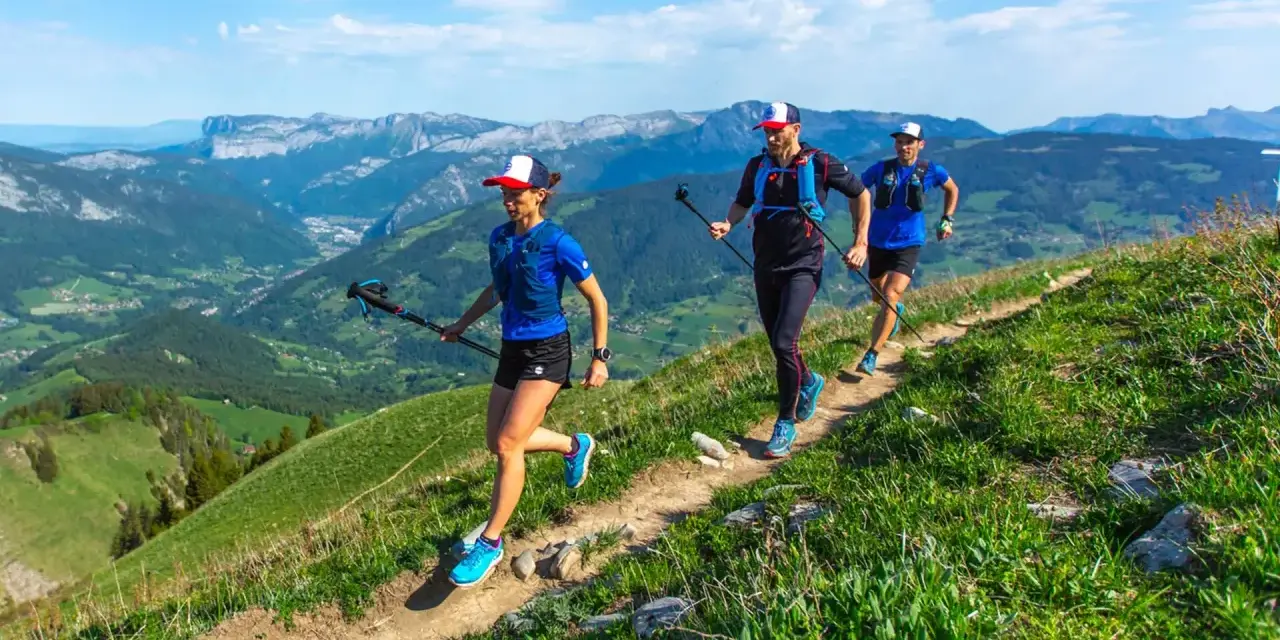 Trzy osoby uprawiające speed hiking na górskim szlaku, ciesząc się pięknymi widokami.