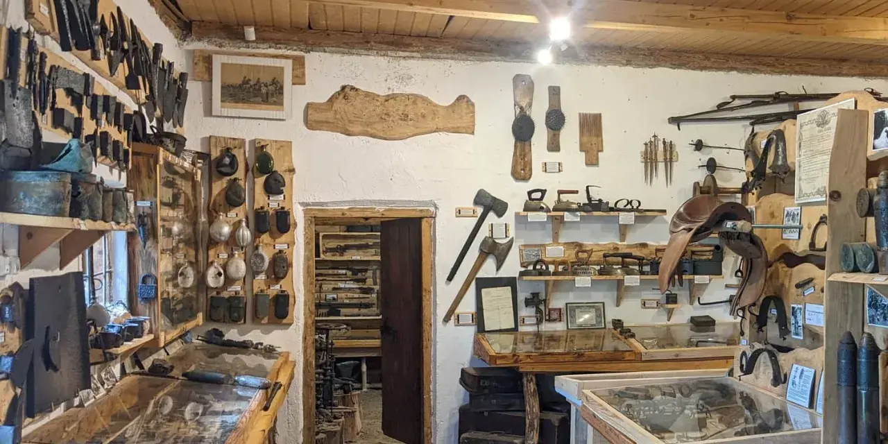 Wnętrze muzeum historii Bieszczad. Eksponaty to narzędzia, broń, siodła i przedmioty codziennego użytku.