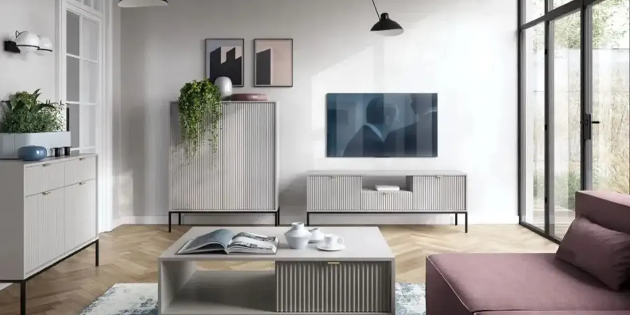 Nowoczesny salon z dużą **ścianą TV**, minimalistycznymi meblami i wygodną, różową sofą.